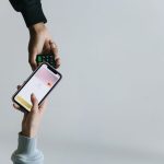 Mãos usando um smartphone e um terminal para realizar um pagamento sem dinheiro em espécie.