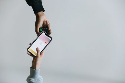 Mãos usando um smartphone e um terminal para realizar um pagamento sem dinheiro em espécie.